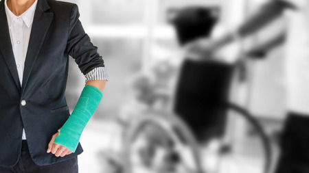 arm broken with green cast on blurred patient sitting in wheelchair background - insurance conceptの写真素材