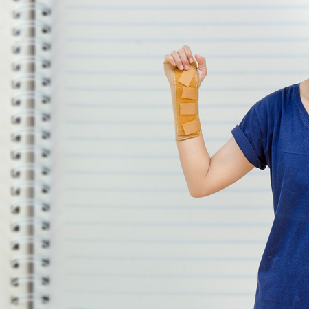 Hand with a wrist brace, orthopedic equipment isolated on white paper in bookの写真素材