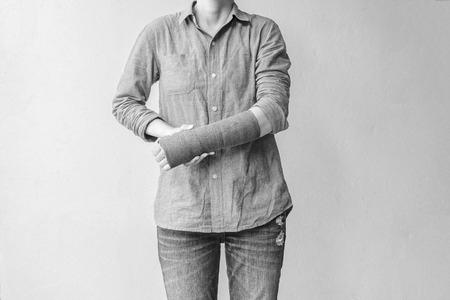 Injured woman with green cast on hand and arm on white background, Travel insurance concept.の写真素材