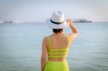 woman standing hold a hat at the sea.の写真素材
