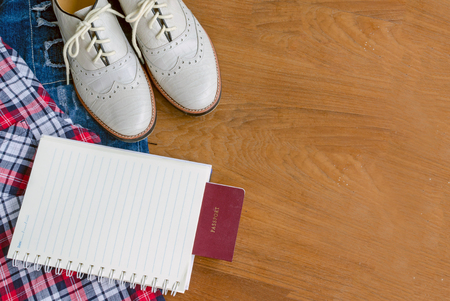 Travel accessories. Vintage leather men's shoes, scott shirt, torn jean, book and passport on wood tableの写真素材