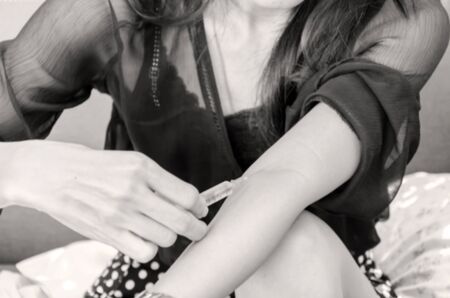 Blurred of woman with syringe making drug injection to himself at home, health care concept.の写真素材