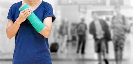 accident on arm, Injured woman with green cast on hand and arm on traveler in motion blur in airport...