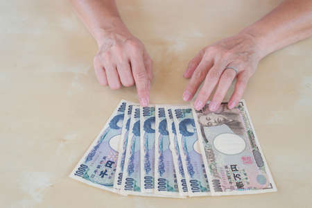 hand woman with Japanese currency yen bank notes.の写真素材