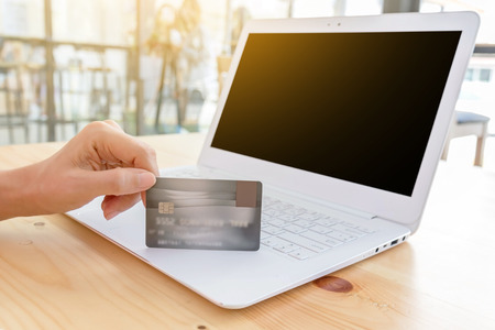 Hands holding plastic credit card with modern white laptop. Online shopping concept.の写真素材