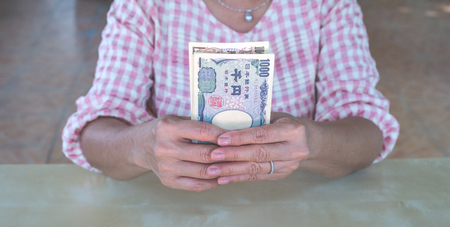 woman hand hold a Japanese currency yen bank noteの写真素材