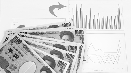 Japanese currency yen bank notes with finance chart and graph on white background, finance planning concept.の写真素材
