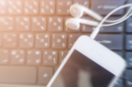 Blurred white phone and headphone on laptop, music digital.の写真素材