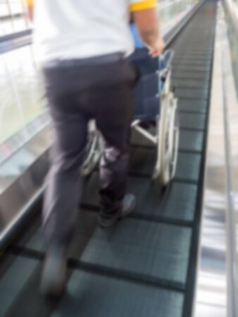 blurred background young man pushing a wheelchair and seniors woman sitting in wheelchair.の写真素材