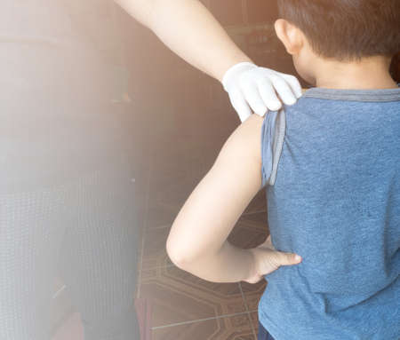 Doctor preparing an injection in the arm boy.