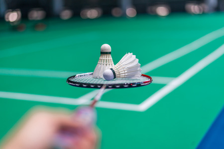 shuttercock on badminton racket with blurred background badminton player, indoor court.の写真素材