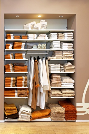 Big storage space with towels on shelf and bathrobes on hangersの写真素材