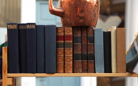 Old grunge books in leather binding on wooden shelfの写真素材