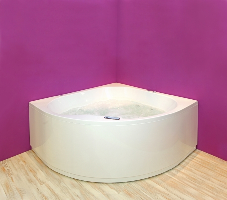 Modern corner hydromassage bathtub with pink wall interiorの写真素材