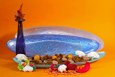 Decorative blue glass plate with potpourri against orange backgroundの写真素材