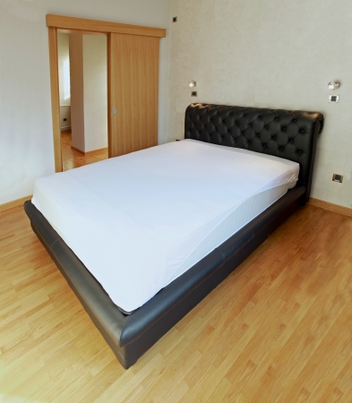 Large leather double bed in empty bedroomの写真素材