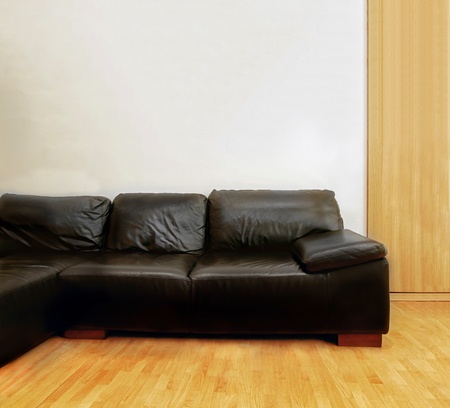 Black leather couch in modern interior with wooden floor and gray wall for copyspaceの写真素材