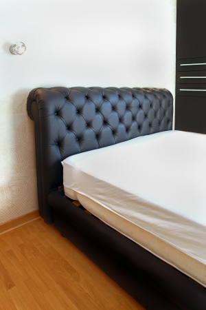 Retro bed with black leather upholstery inside modern bedroomの写真素材
