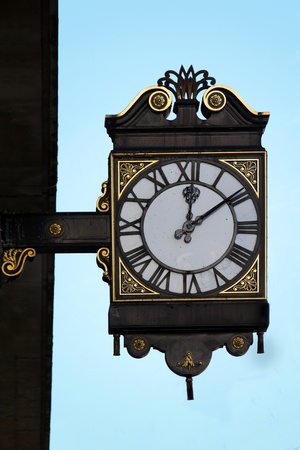 Vintage public clock hanging from building with gold ornamentsの写真素材