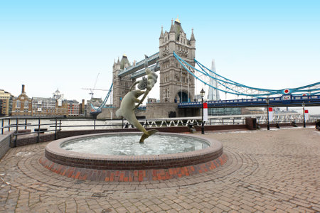 Girl with a dolphine fountain on St Katherine Dock next to Tower bridgeのeditorial素材