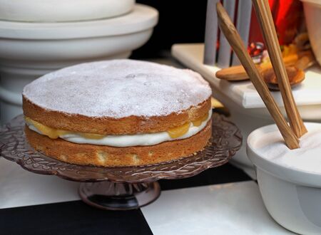 Sponge cake on glass plate with sugar bowl on the sideの写真素材