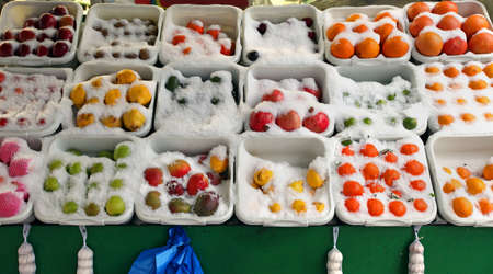 Variety of fruits inside crates on market stall under snow during winterの写真素材