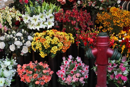 Bunch of attractively arranged flower bouquets next to hydrantの写真素材