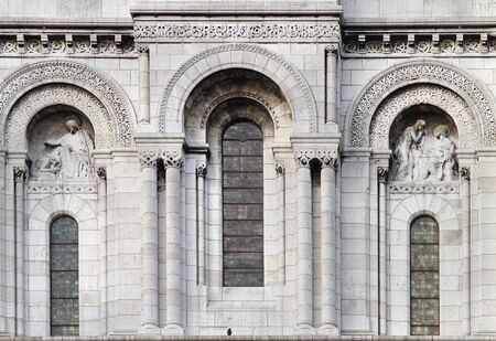 Old stone facade with tall windows and sculpture ornamentsの写真素材