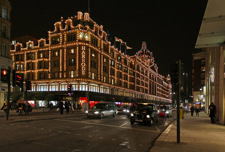 London, United Kingdom - January 22, 2013; Famous department store Harrods in London during holiday seasons with festive decoratons during night with traffic and people walking by on the street のeditorial素材