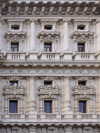 Old urban building stone facade with tall windowsの写真素材