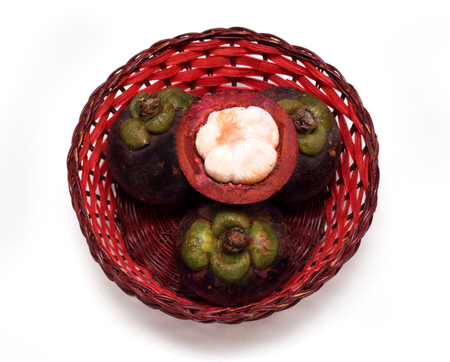 Mangosteen fruit opened cut in half in rattan basket の写真素材