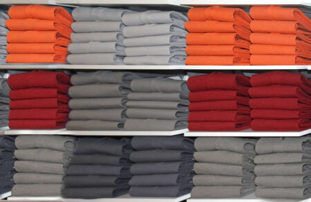 Colorful neatly folded t-shirts on shelf in retail storeの写真素材