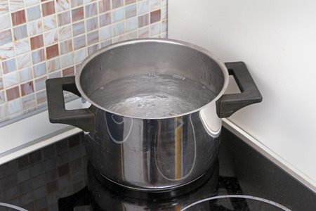 Water boiling in a pot on stove in modern kitchen