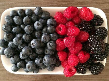 Fresh organic berries pile on white plateの素材