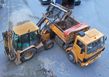Digging road works on small street with industrial machinesの写真素材