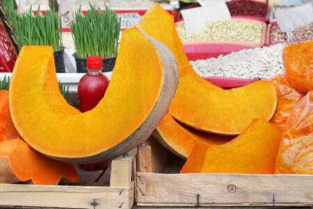 Sliced pumpkin in wooden crate on market stallの写真素材