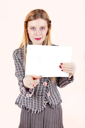 Young woman holding empty white paper and pointing finger towards youの写真素材