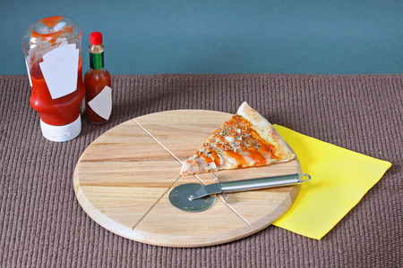 Cut out triangle of pizza on circle wooden chopping boardの写真素材