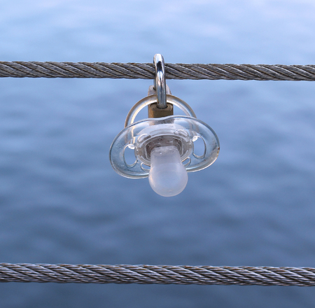 Baby dummy attached to padlock hanging on a string