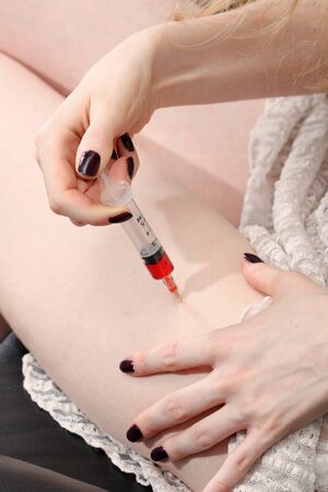 Woman giving herself injection into thigh muscleの写真素材