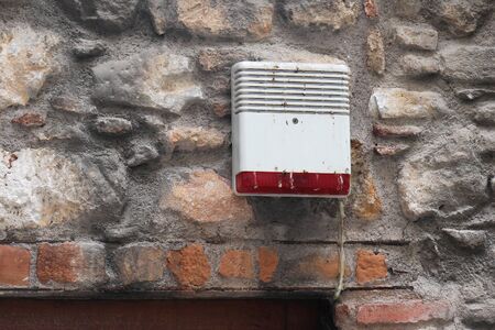 Old dirty burglar alarm on facade of stone house