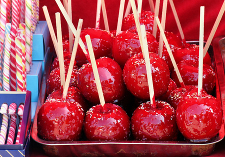 Red caramelized sweet apples on wooden stick sold on market fairの写真素材
