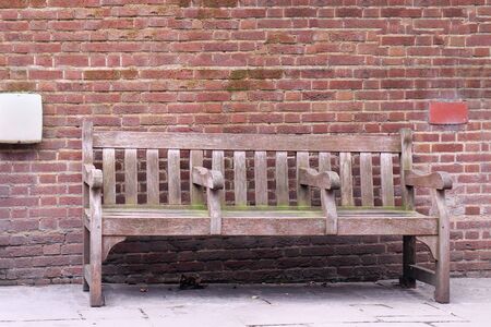 Retro wooden bench with brick wall in backgroundの写真素材