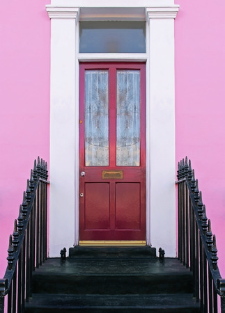 Retro red entrance door on house with pink facadeの写真素材