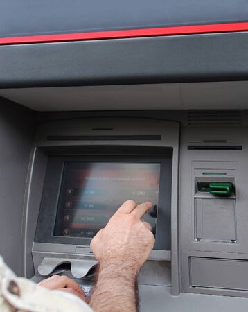 Man selecting amount to withdraw from ATMの写真素材