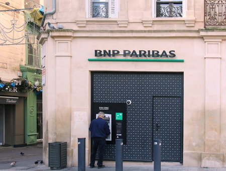 ARLES, FRANCE - JANUARY 29; Man in front of BNP Paibas bank machine withdrawing cash in Arles, France - January 29, 2016: Man making cash withdrawal in small empty street.のeditorial素材