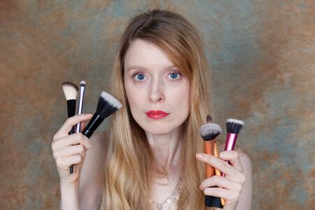 Young beautiful girl holding make up brushesの写真素材