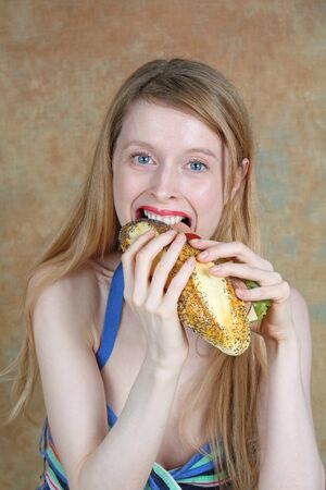 Young blonde girl eating healthy tasty sandwichの写真素材