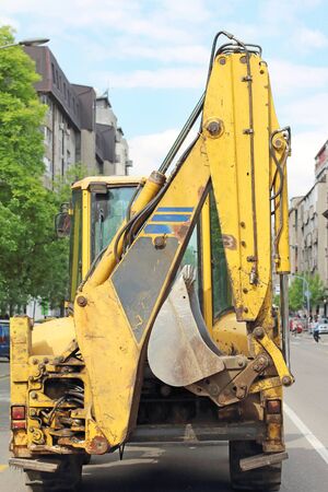 Dirty industrial digger machine on urban roadの写真素材