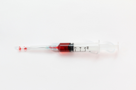Syringe full with red medicine on white backgroundの写真素材